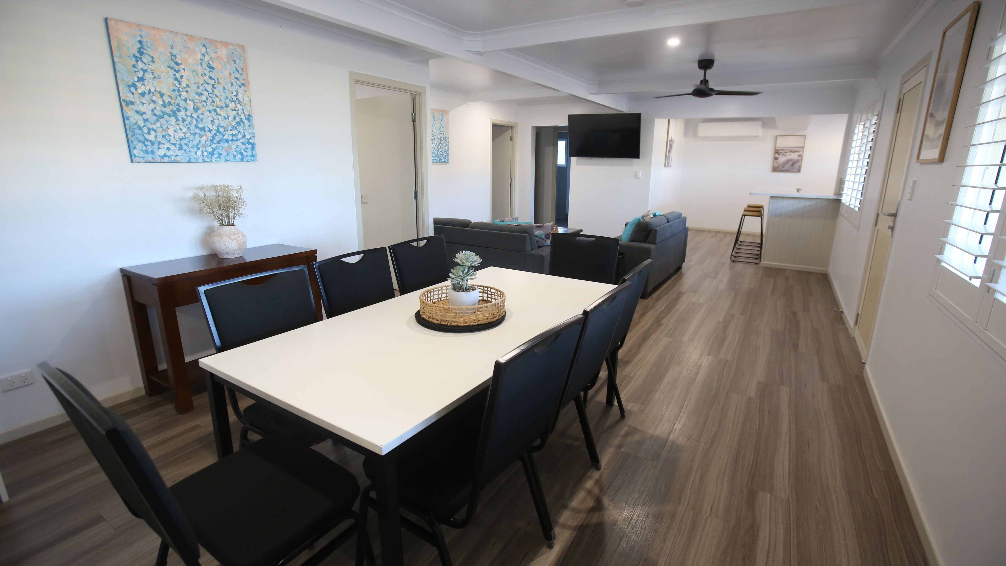 Un comedor con una larga mesa, sillas y un centro de mesa decorativo con plantas.