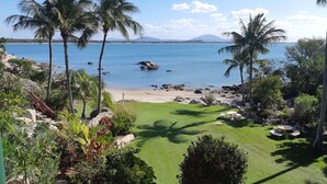 A tropical beach with palm trees, a grassy area, and a view of the sea. - Whitsunday Sands Resort (Bowen)
