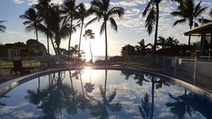 A swimming pool with reflections of palm trees and a sunset. - Whitsunday Sands Resort (Bowen)