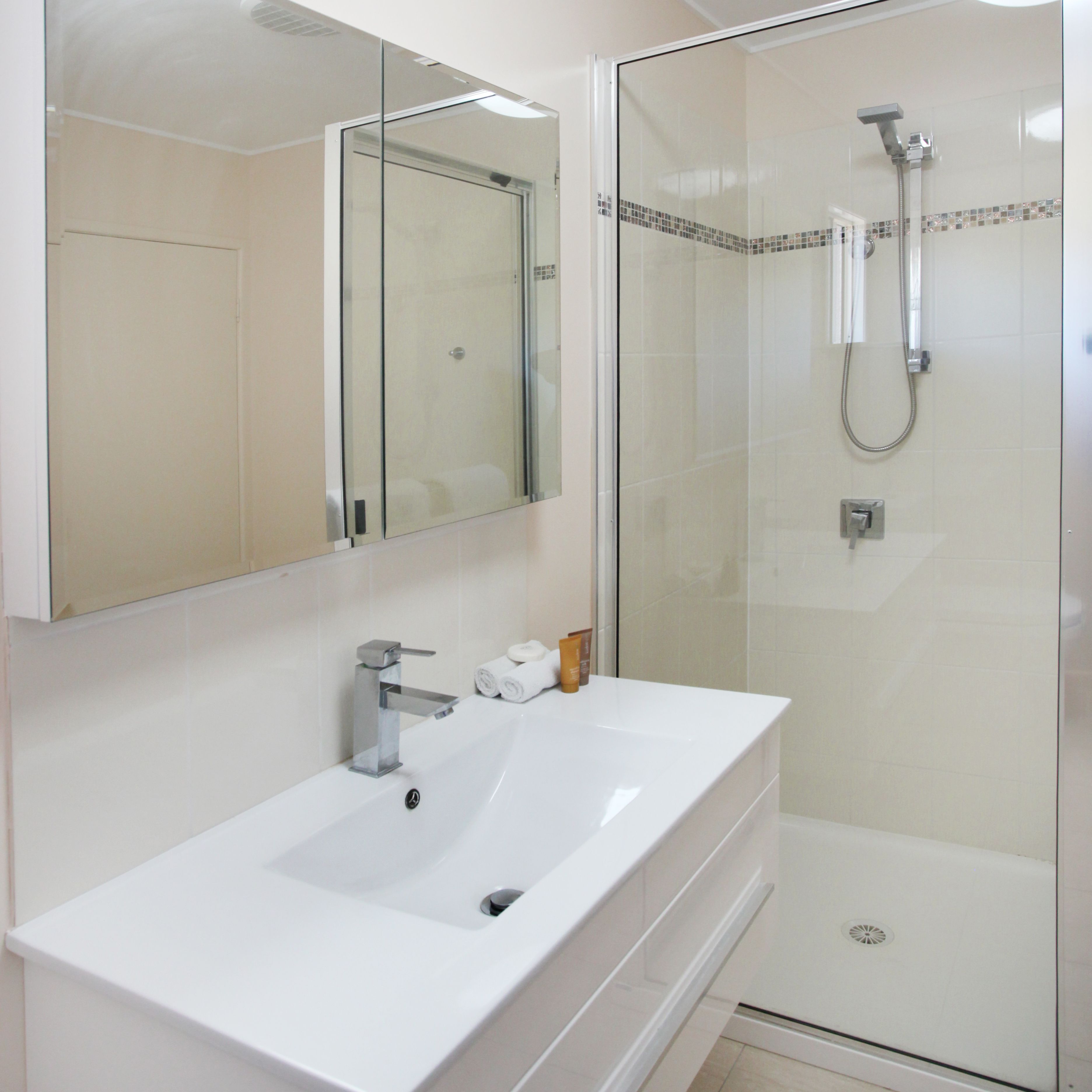 A bathroom with a white sink, a mirror, and a glass-enclosed shower area.
