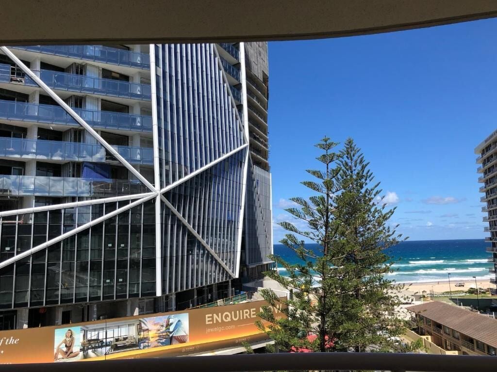 A modern building with a glass facade and a view of the beach.