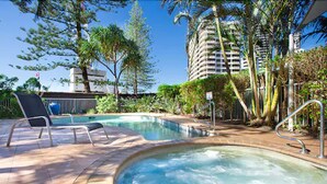 A pool area with a hot tub, lounge chairs, and surrounding greenery. - Wharf Boutique Apartments (Surfers Paradise)