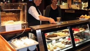 A buffet area with various food items displayed in glass cases, a coffee shop counter, and a sign for a liquor shop in the background. - Rich River Golf Club Resort (Moama)