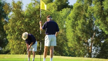 Un campo da golf con due giocatori che si preparano a tirare.