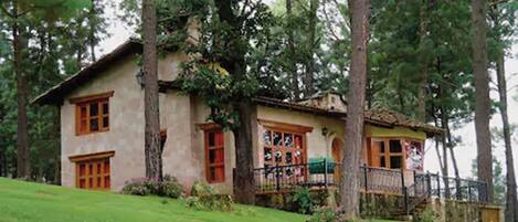 A two-story house with a balcony, surrounded by trees.