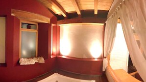 Una habitación con techo de madera, un ventanal con cortinas, una bañera y un ventanuilla con vistas al exterior.