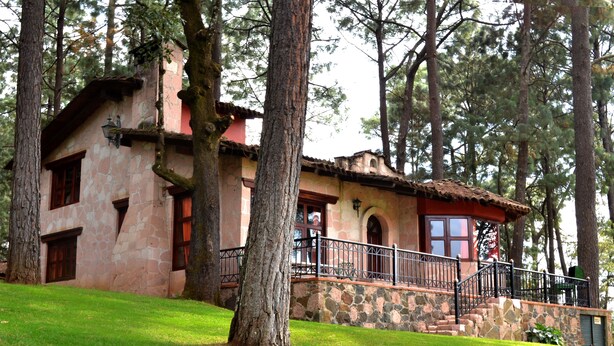 Un edificio de piedra con techo rojo, una escalera de piedra y una barandilla de metal.