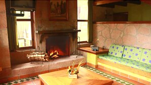 Una sala de estar acogedora con chimenea, una mesa de centro de madera y un sofá verde estampado.