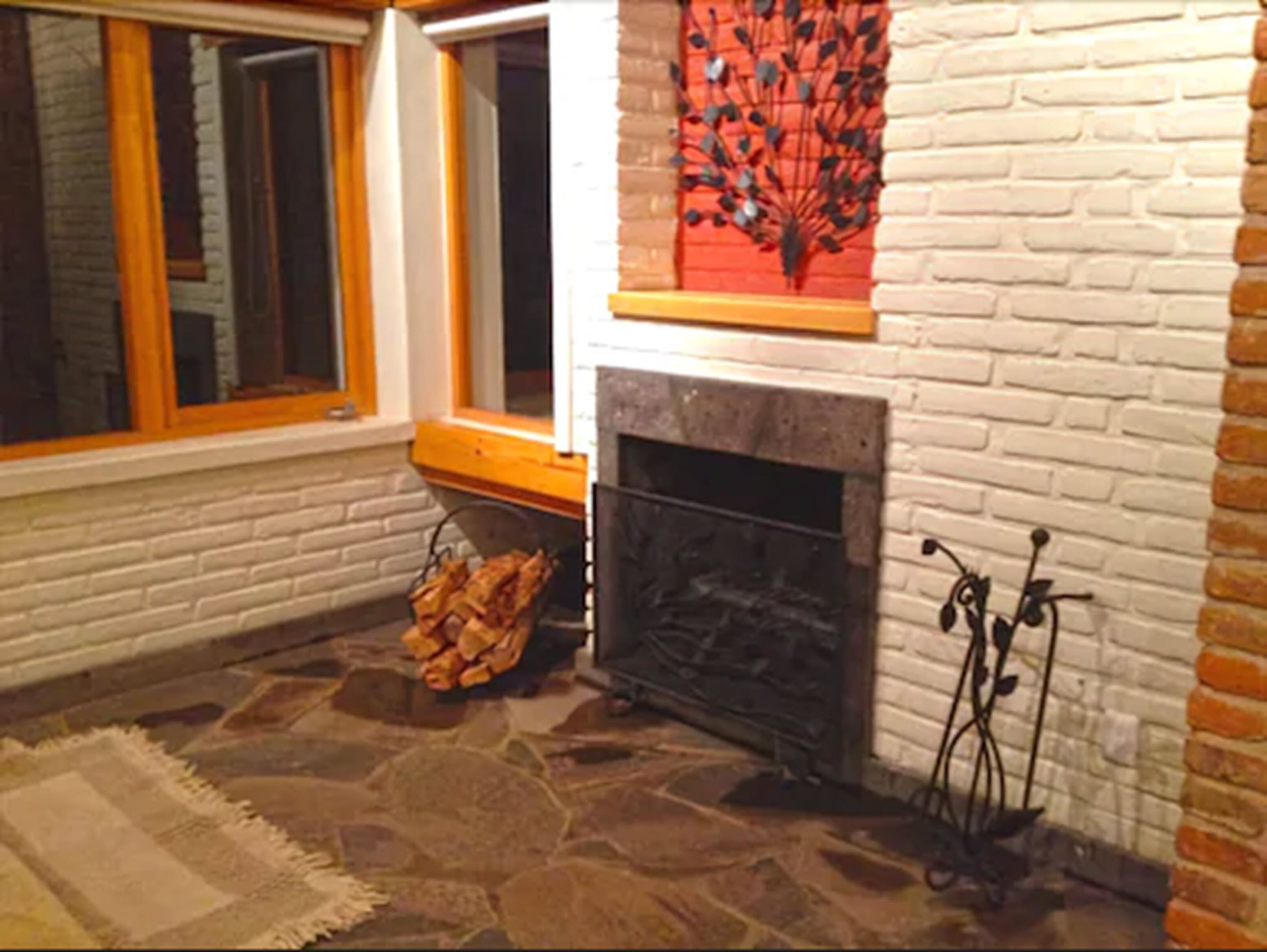 Una habitación con chimenea de piedra, ventana con marco de madera y pared de ladrillo.