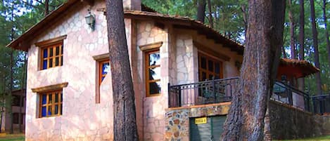 Una casa in pietra con camino in pietra, finestre in legno e un piccolo balcone.