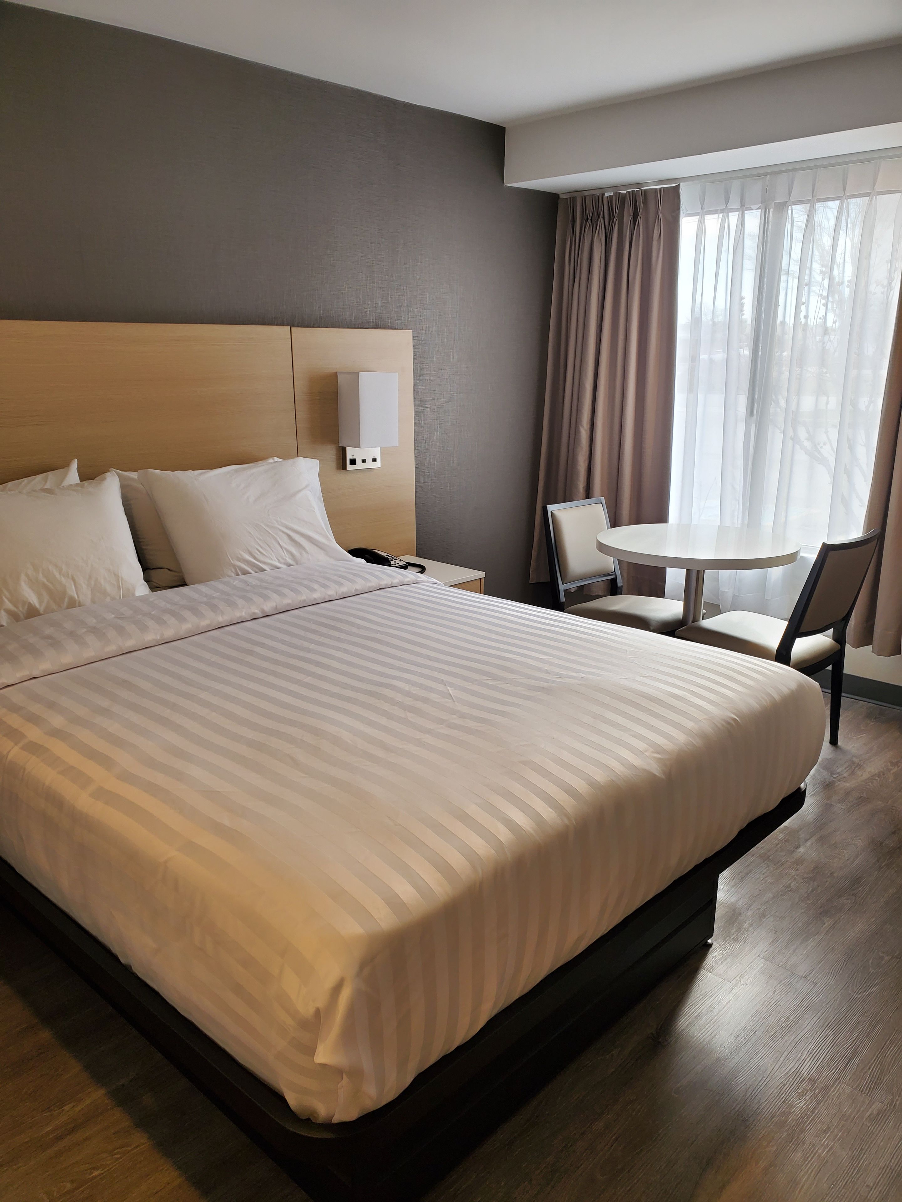 A hotel room with a large bed, bedside tables, a desk, and a chair.