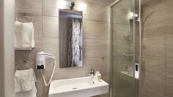 A modern bathroom with a glass shower enclosure, a white sink with a mirror above it, and two towel racks with white towels.