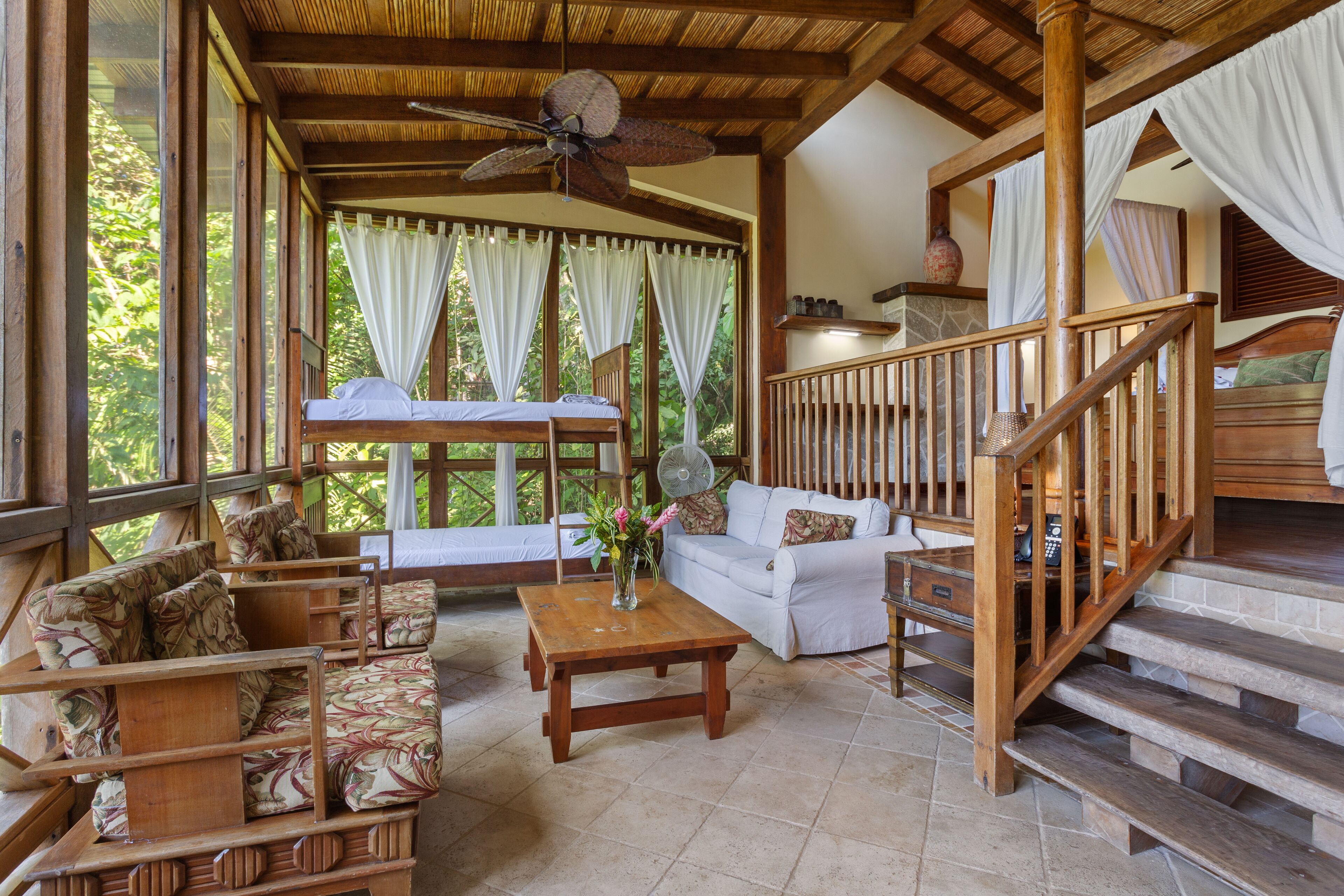 A wooden-floored room with a bed, sofa, and a staircase.