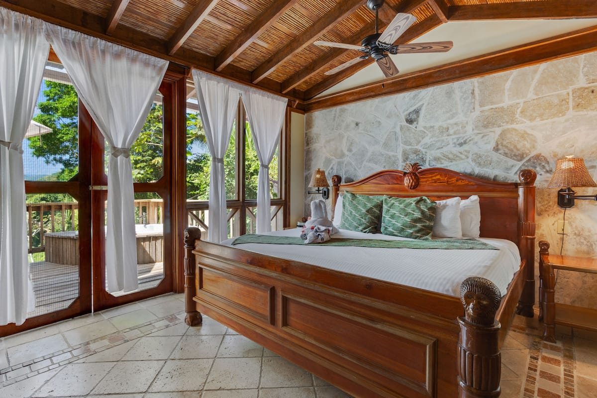 Een slaapkamer met een houten bed, stenen muren en uitzicht op de omgeving.