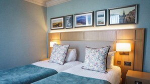A double bed with floral-patterned pillows, a wooden headboard, and a nightstand with a lamp. - Parliament House Hotel (Edinburgh)
