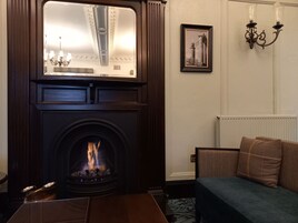 A cozy living room with a fireplace, a sofa, a table, and a framed picture on the wall.