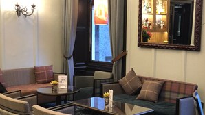 A hotel room with a sofa, armchairs, a coffee table, and a mirror. - Parliament House Hotel (Edinburgh)