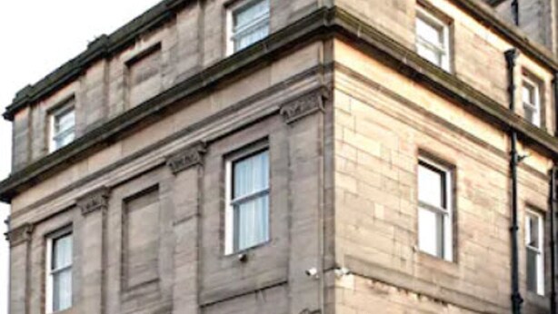 A multi-story stone building with a symmetrical facade, large windows, and a central entrance with a door. - Parliament House Hotel (Edinburgh)
