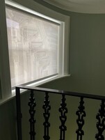 Een raam met uitzicht op een gevel, een zwarten balustrade en een groene muur.