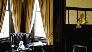 A room with a black leather armchair, a small round table, and a decorative golden statue. - Parliament House Hotel (Edinburgh)