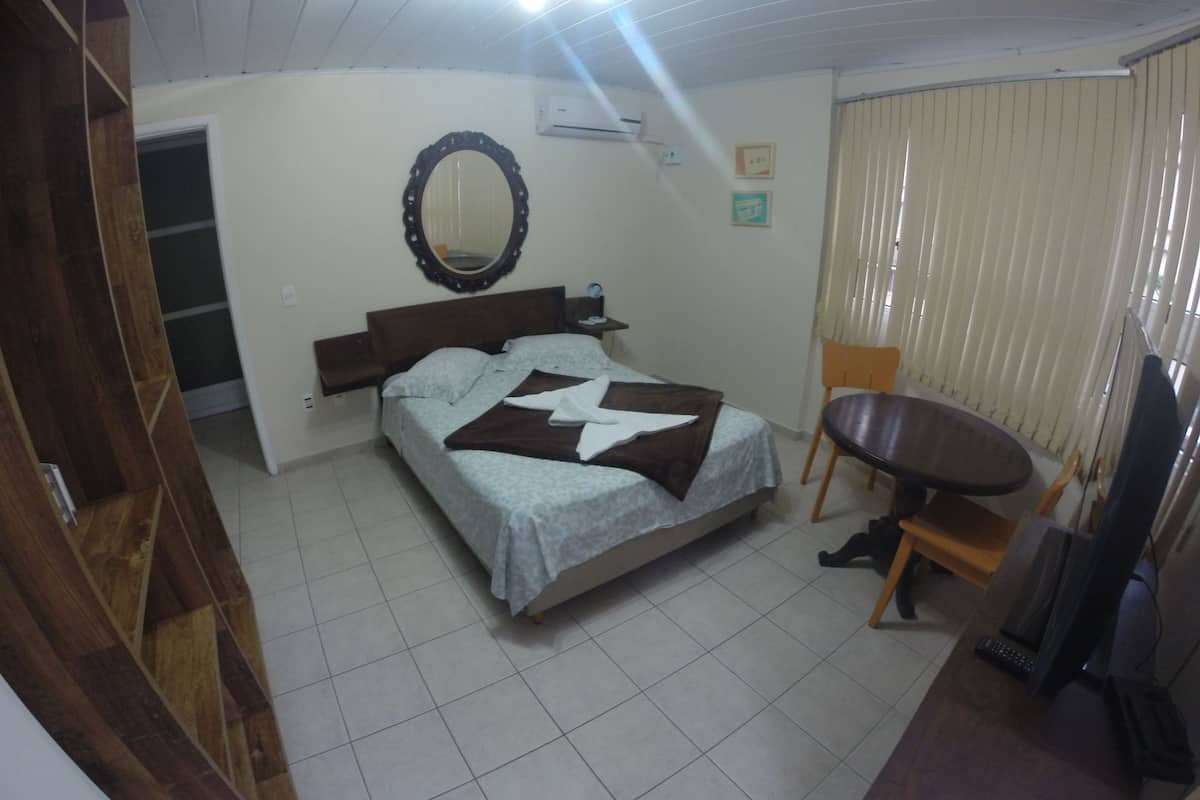 Ein Schlafzimmer mit Bett, Stuhl, Schreibtisch und Spiegel.