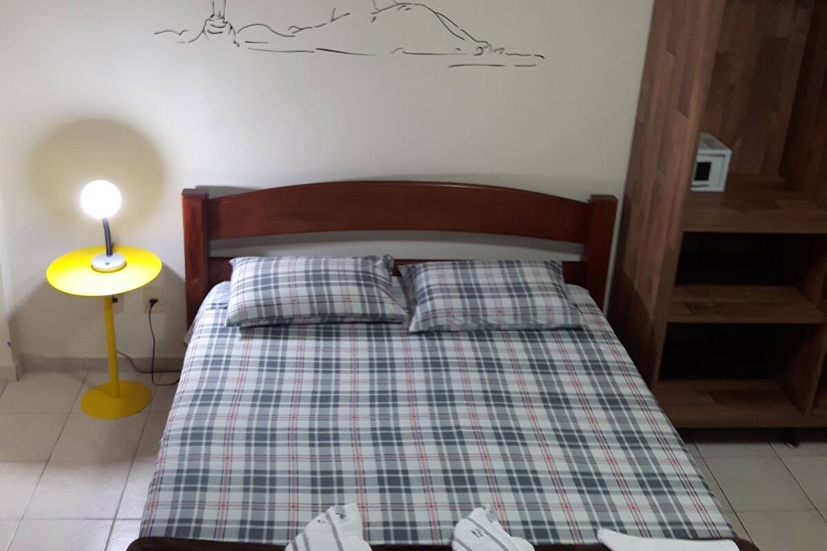 Ein Schlafzimmer mit einem Bett, einer Nachttischlampe, einem Holzschrank und einer Wand mit einer schlichten Linienzeichnung.