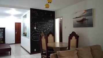 Una sala de estar con comedor, una pizarra con escritura, un cuadro y una puerta de madera.