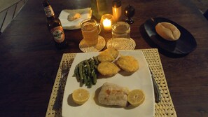 Una mesa con un plato de comida, una botella de cerveza y una vela.