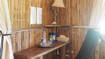 Una habitación rústica de madera con una mesa, una silla, una lámpara colgante y un pequeño estante con objetos.