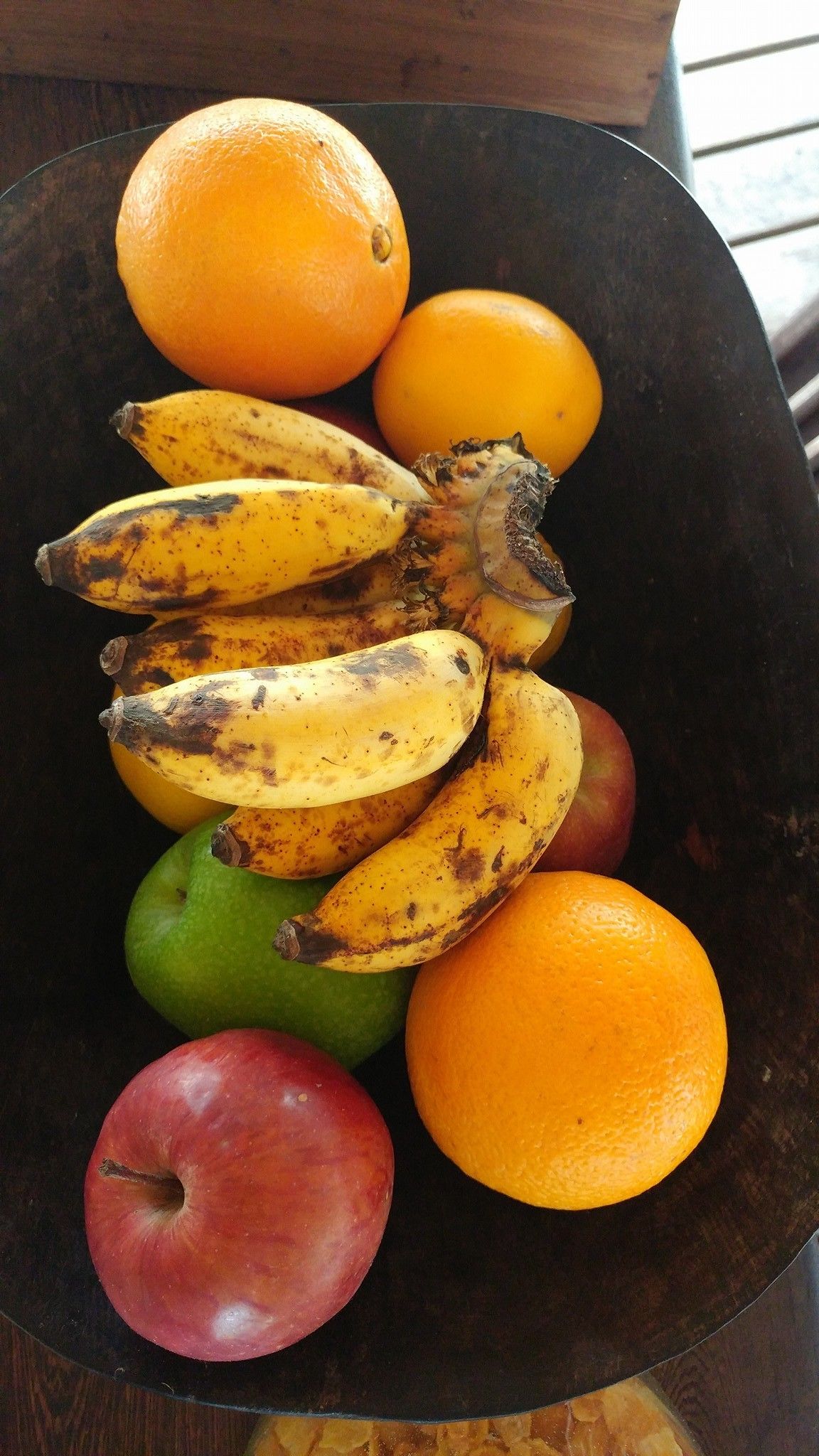 Una ciotola con diversi tipi di frutta, tra cui banane, arance e mele.