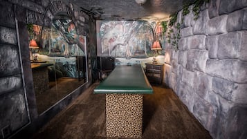 A room with a stone wall, a green bench, and a mural of a jungle scene.