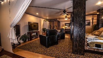 A room with a bed, a TV, a sofa, and a ceiling fan.