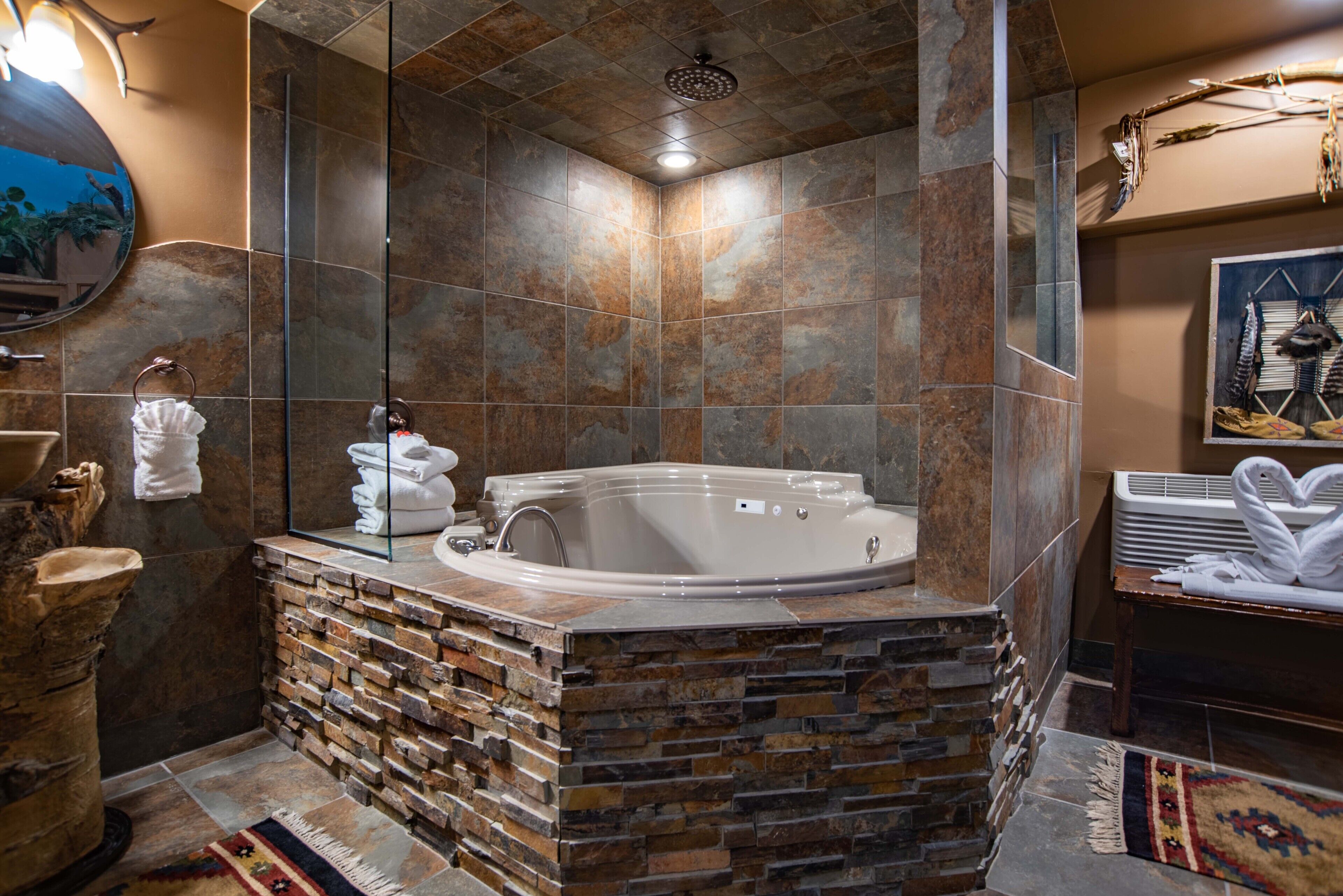 A modern bathroom with a stone wall, a large bathtub, and a mirror.