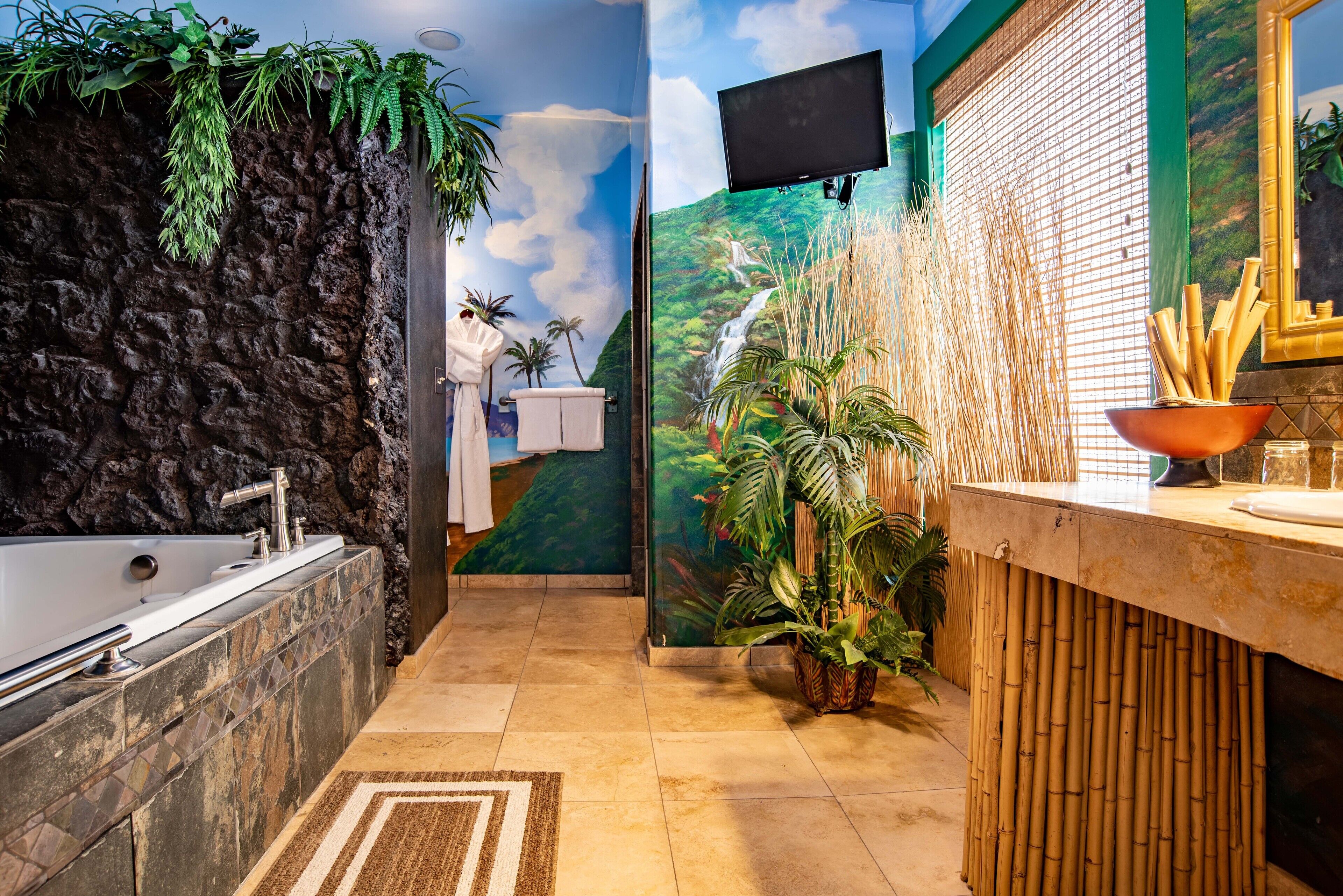 A bathroom with a stone wall, a bathtub, a sink with a bamboo-themed counter, and a mural of a waterfall.