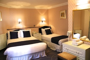 A hotel room with two beds, bedside lamps, a dresser, a mirror, and a telephone.