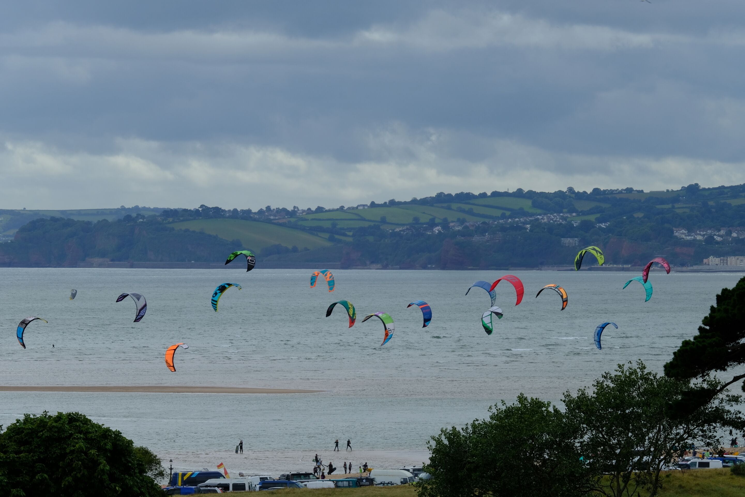 Une zone côtière où l’on peut pratiquer de nombreuses activités de kitesurf, avec une plage de sable et une ville située au loin.