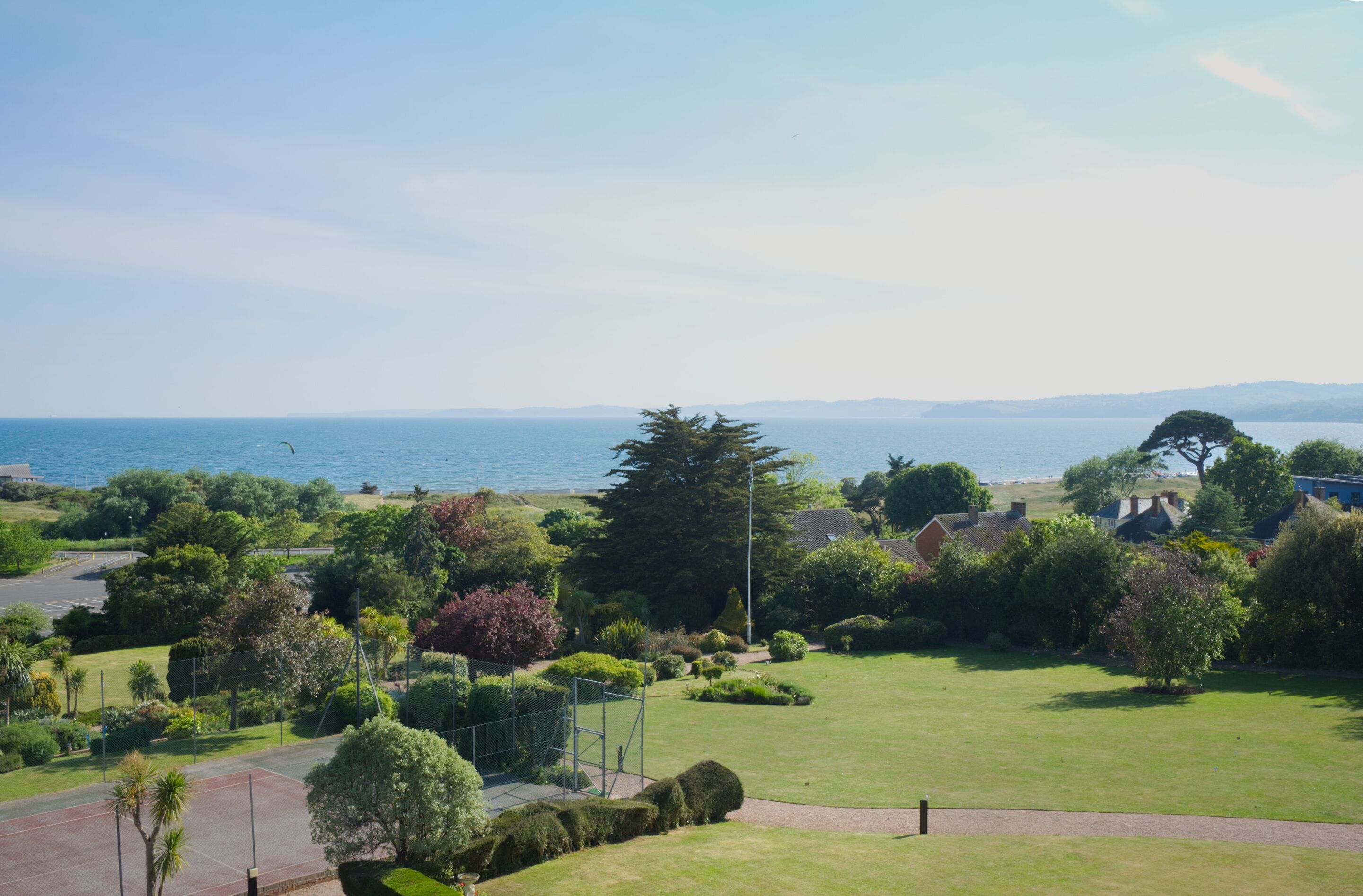 Zona residencial con vista al mar, casas y una cancha de tenis.