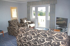 A hotel room with a sofa set, a television, and a view through the door. - The Devoncourt Resort (Exmouth)