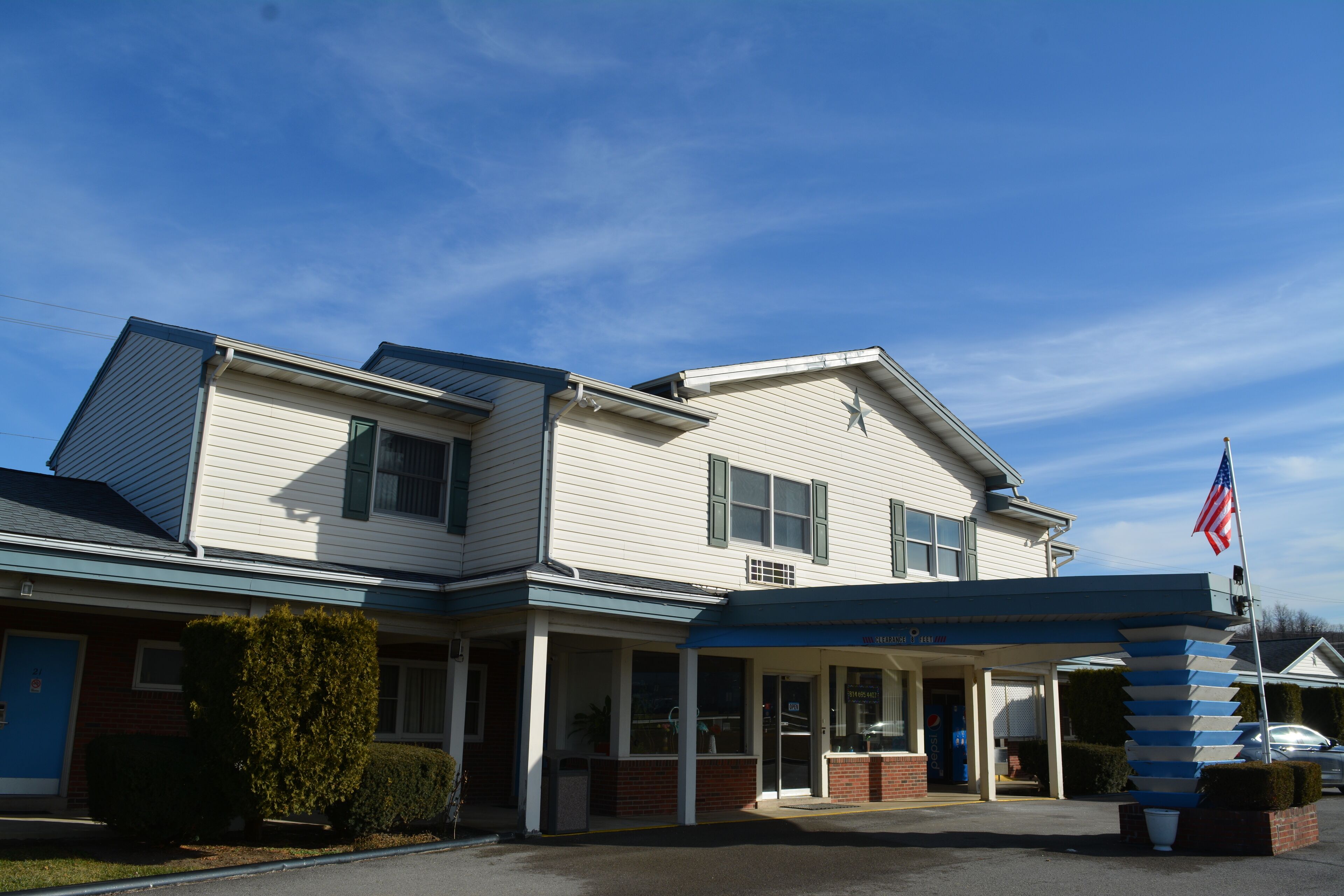A two-story building with a covered entrance and a flagpole with an American flag.