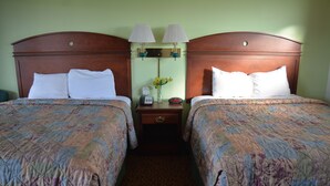 A hotel room with two beds, each with a wooden headboard, a nightstand with a lamp, a vase with flowers, and a telephone. - WYE Motor Lodge Duncansville - Altoona (Hollidaysburg)