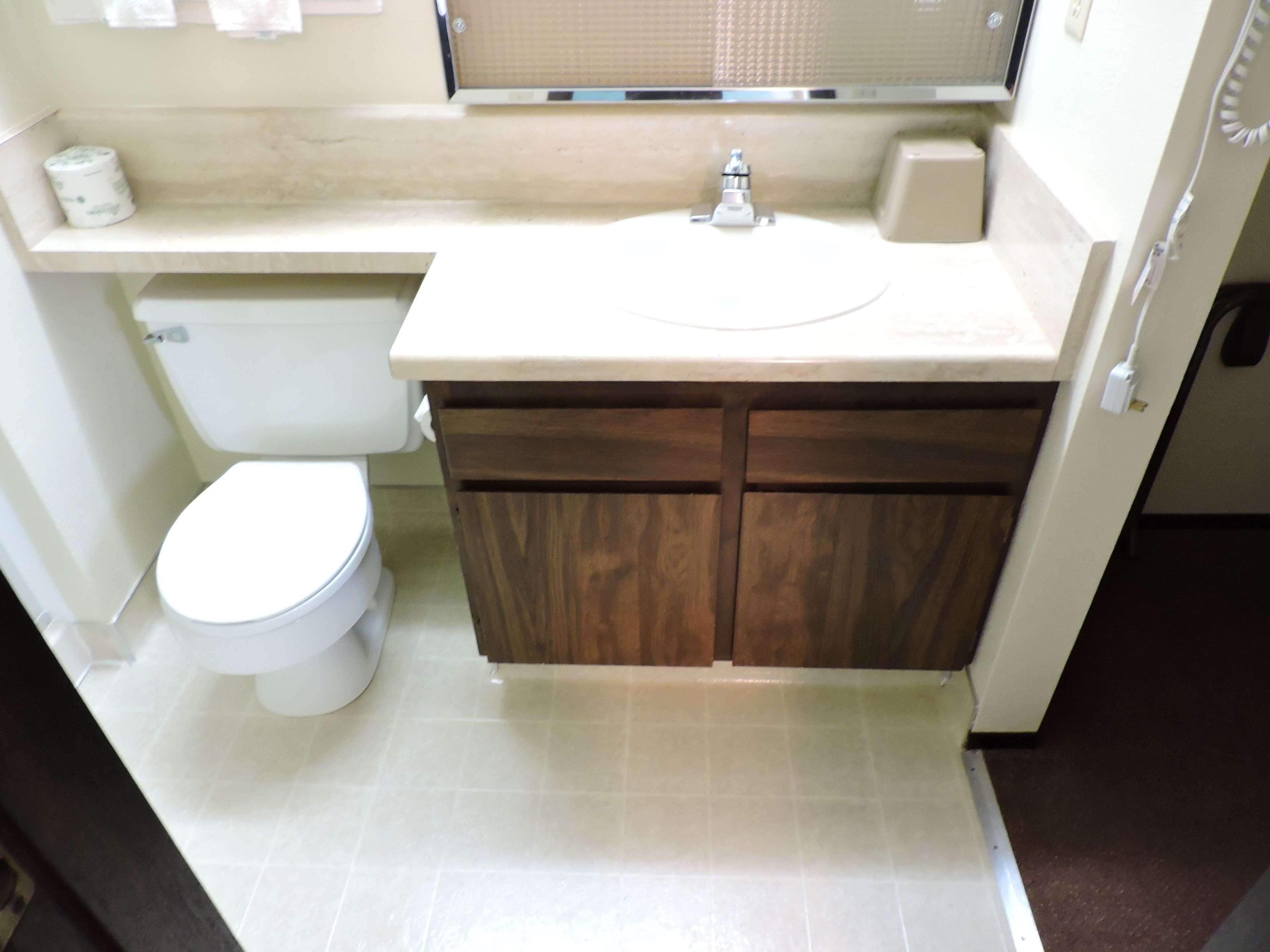 Un baño con inodoro, lavamanos y armarios de madera.