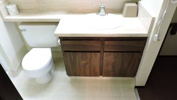 Un baño con inodoro, lavamanos y armarios de madera.