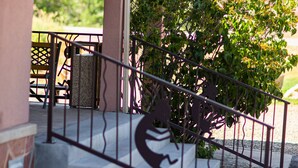 A covered outdoor area with a metal railing, a bench, and a planter with greenery. - Kokopelli Inn (Bluff)