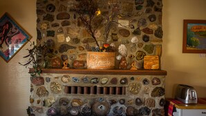 A stone fireplace with a wooden mantel, surrounded by various decorative items and a framed picture on the wall. - Kokopelli Inn (Bluff)