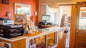A reception area with a wooden counter, a computer, and a glass display case with pastries. - Kokopelli Inn (Bluff)