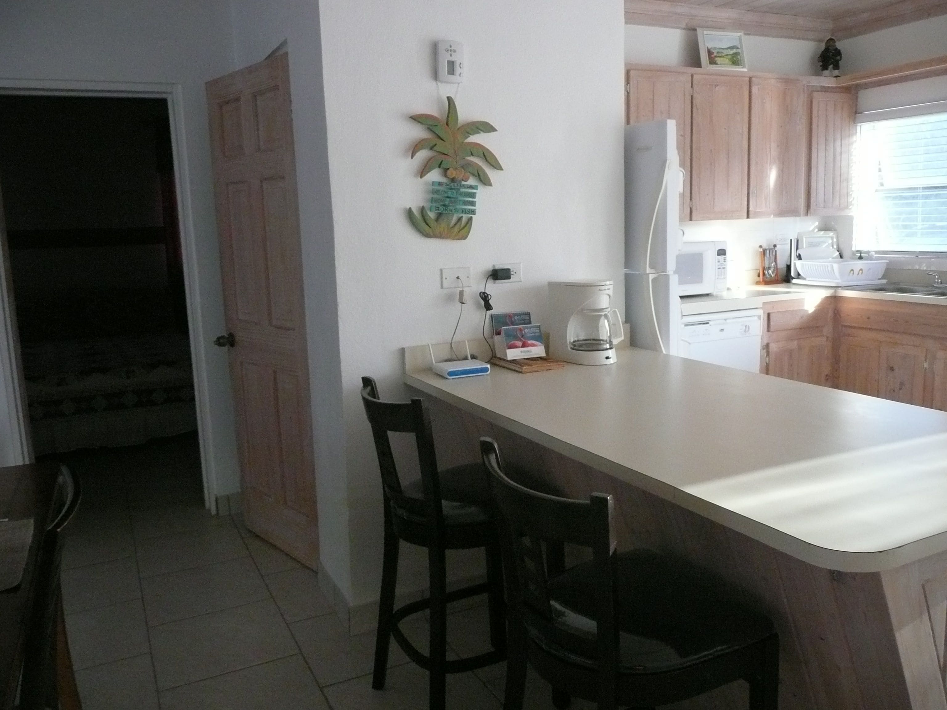 A kitchen with wooden cabinets, a white countertop, a coffee maker, and a refrigerator.