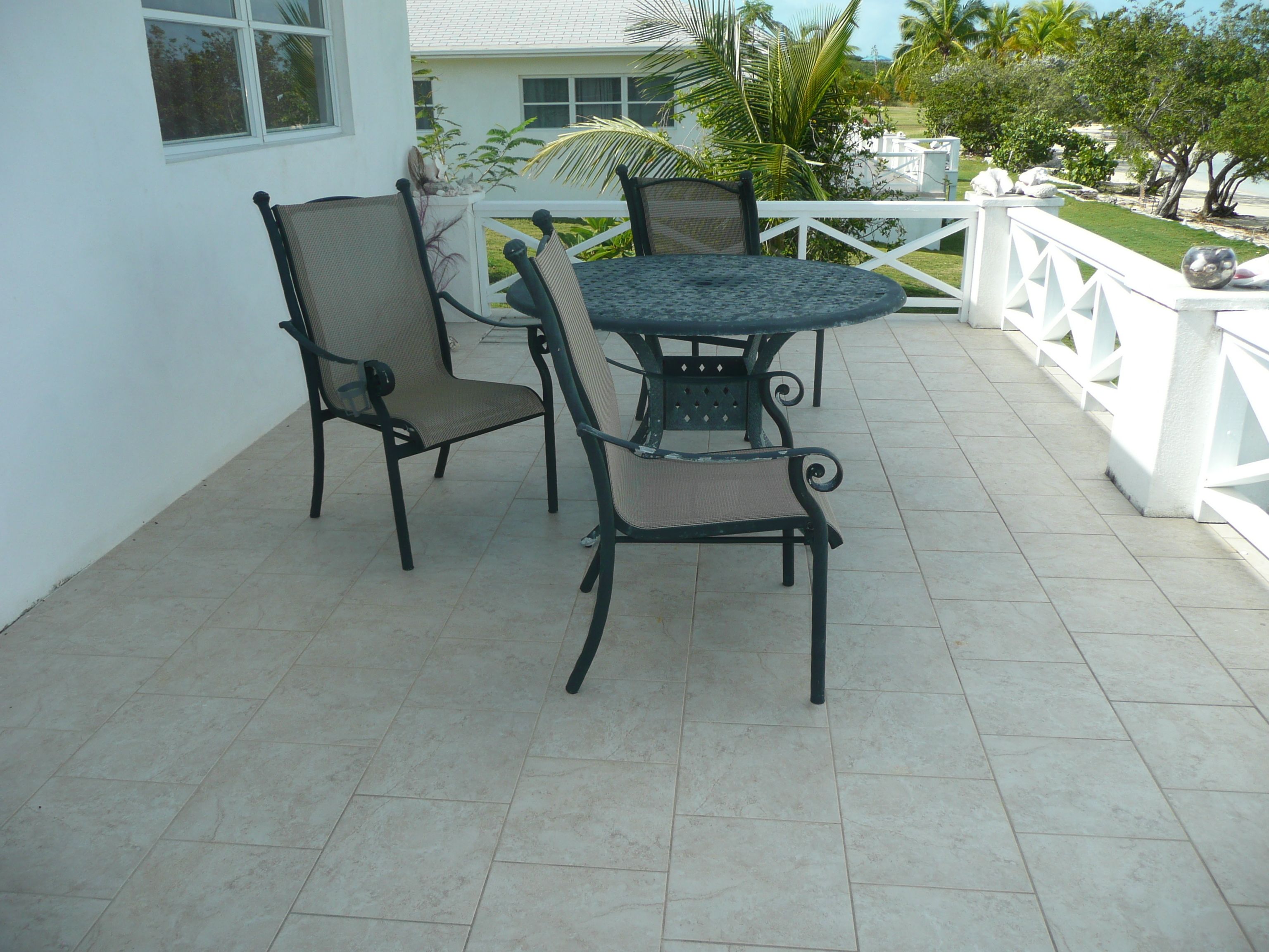 A patio with a round table and four chairs, surrounded by a white railing.
