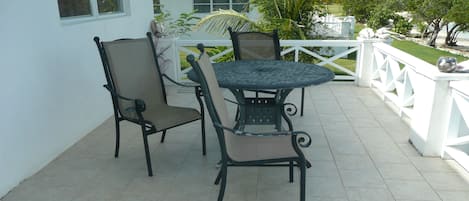 A patio with a round table and four chairs, surrounded by a white railing.