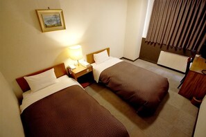 Habitación de hotel con dos camas, una mesita de noche, una lámpara, un cuadro en la pared y una ventana con cortinas.