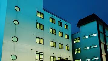 A multi-story hotel with a modern design, featuring a flat facade and circular windows.